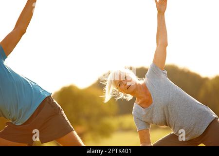 Flexibel bleiben. Ein reifes Paar, das im Freien Yoga macht Stockfoto