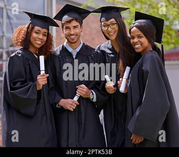 Unsere Zukunft auf harter Arbeit aufbauen. Lächelnde Universitätsstudenten am Abschlusstag Stockfoto