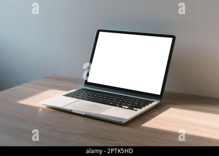 Laptop-Computer mit leerem Bildschirm auf dem Schreibtisch. Wird zum Einfügen von Text oder Werbung verwendet. Stockfoto