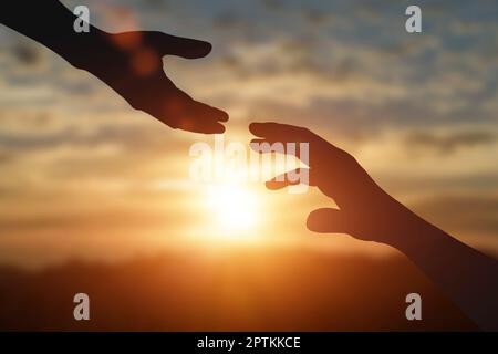 Silhouette aus Greifkraft, helfender Hand, Hoffnung und gegenseitiger Unterstützung bei Sonnenuntergang. Hilfe, Freundschaft, internationales Tageskonzept. Stockfoto