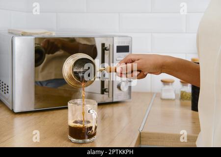 Nahaufnahme des Ausgießens von heißem Kaffee in die Tasse Stockfoto