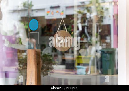 Am Eingang hängt ein Schild mit der Aufschrift „Offen“ auf lokalen Unternehmen. Sagen Sie Willkommen. Klappschild zum Öffnen und Schließen vor der Glastür. Stockfoto