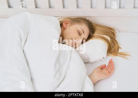 Junge, schöne Frau schläft im Schlafzimmer mit langen Haaren auf dem Kissen Stockfoto