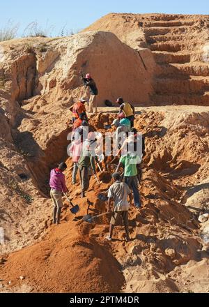 Ilakaka, Madagaskar - 30. April 2019: Gruppe unbekannter madagassischer Männer, die Saphir im Tagebau abbauen, indem sie an einem sonnigen Tag den Boden mit Schaufeln bewegen. Thi Stockfoto