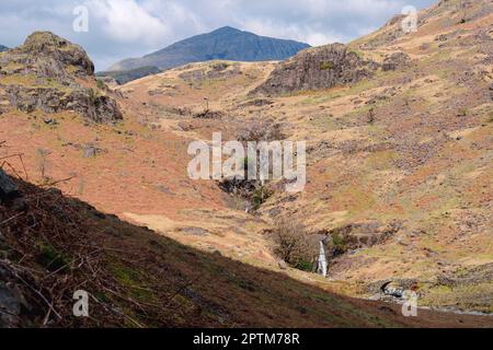 Lingcove Bridge über Lingcove Beck mit Wasserfällen, die in die oberen Bereiche des Esk fließen. ESK Pike, der Berg im Hintergrund. Westliche Seen Stockfoto