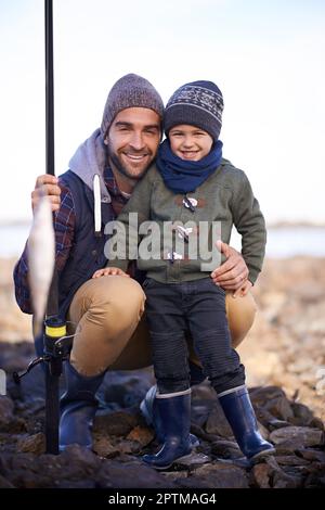 Rate mal, was wir zum Abendessen haben. Porträt eines liebenden Vaters und Sohnes mit den Fischen, die sie zusammen gefangen haben Stockfoto