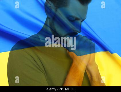 Doppelte Exposition der Nationalflagge und des betenden Mannes. Beenden Sie den Krieg in der Ukraine Stockfoto