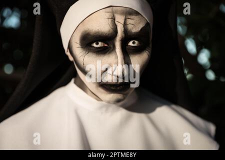 Porträt einer teuflischen Nonne draußen, Nahaufnahme. Halloween-Party-Look Stockfoto