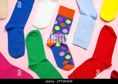 Viele verschiedene bunte Socken auf hellrosa Hintergrund, flach liegend Stockfoto