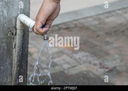 Alter Wasserhahn und Hand sind offenes Wasser. Stockfoto