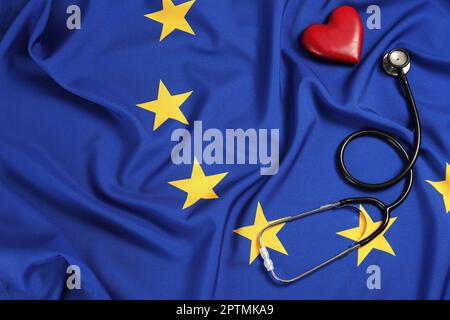 Stethoskop und rotes Herz auf der Flagge der Europäischen Union, flach liegend. Platz für Text Stockfoto