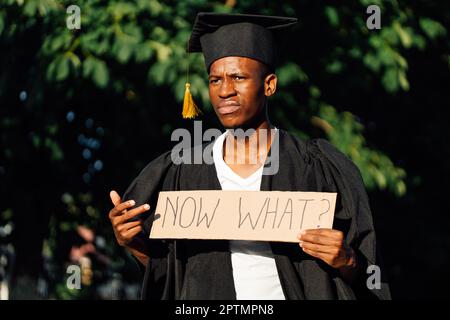 Porträt eines unzufriedenen afroamerikanischen Typen, der auf ein Plakat auf der Straße zeigte. Suche nach Arbeit, Einstellung und Beschäftigung. Universität Stockfoto