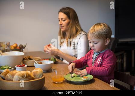 Kleiner Junge, der Butter auf Brot schmiert, München, Deutschland Stockfoto