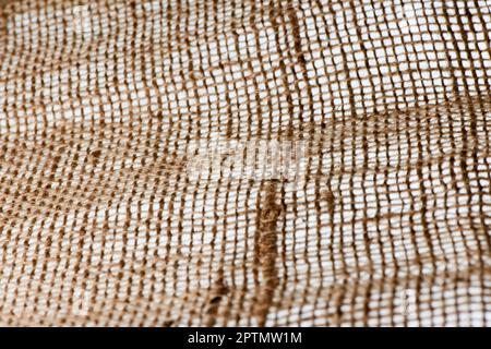 Vollformatansicht von grobem Textilgewebe mit Schärfeverlauf auf weißem Hintergrund mit Hintergrundbeleuchtung. Stockfoto