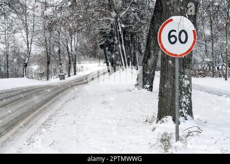 Straßenschild mit Geschwindigkeitsbegrenzung von 60 km/h auf verschneiter Straße. Winterlandschaft. Stockfoto