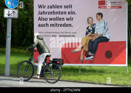 Ein großes Poster als Aufruf zur Wahl der Sozialwahlen 2023 am 31. Mai 2023 befindet sich auf einer belebten Straße, ein Radfahrer fährt davor. Sie findet alle sechs Jahre bei allen gesetzlichen Renten-, Kranken- und Unfallversicherungen statt. Oberhausen, 27. April 2023 Stockfoto