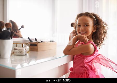 Ich werde genauso aussehen wie meine Mami. Porträt eines kleinen Mädchens, das einen Blusher im Spiegel aufträgt Stockfoto