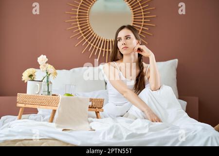 Traumhaftes und luftiges Mädchen im Bett am Morgen Stockfoto