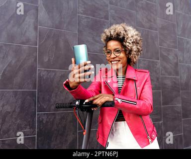 Eine afroamerikanische Frau, die das Handy auf der Straße benutzt Stockfoto