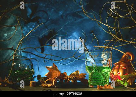 Halloween-Cocktail. Halloween-Design mit Kürbiskopf-Jack-Laterne im Wald mit gruseligen schwarzen Bäumen, alten Blättern, Spinnen und Fledermäusen. Jack O' Lanterns Stockfoto