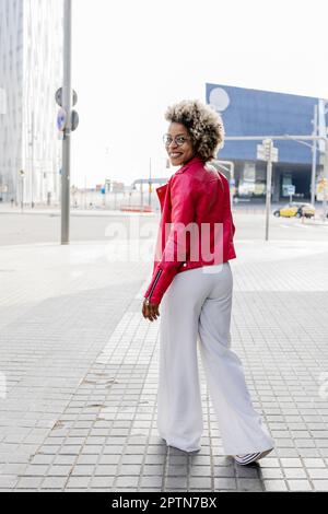 Rückansicht einer Frau in pinkfarbener Jacke, die die Straße entlang läuft