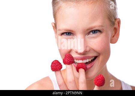 Fingerfood-Spaß. Eine schöne junge Frau, die Himbeeren von ihren Fingerspitzen isst Stockfoto