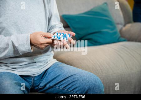 Asian besorgt Senior Mann mit Medikamenten Pillen, um auf dem Tisch im Wohnzimmer zu nehmen, alter Mann kaufen pflanzliche Selbstheilung Rx Pille online aus der Apotheke, ist zu Hause Stockfoto