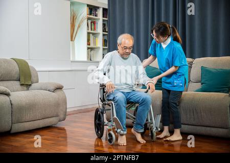 Arzt unterstützt alten Mann beim Aufstehen zum Sport, behinderten älteren Menschen beim Aufstehen helfen, asiatische Krankenschwester hilft älteren Patienten vom Wheelcha aufzustehen Stockfoto