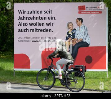 Ein großes Poster als Aufruf zur Wahl der Sozialwahlen 2023 am 31. Mai 2023 befindet sich auf einer belebten Straße, ein Radfahrer fährt davor. Sie findet alle sechs Jahre bei allen gesetzlichen Renten-, Kranken- und Unfallversicherungen statt. Oberhausen, 27. April 2023 Stockfoto