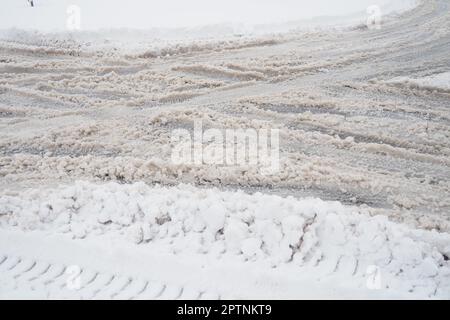 Eine Gabel oder ein Schild aus einem Kreisverkehr. Schneeverwehungen am Straßenrand. Schlechtes Wetter und Verkehr. Schnee auf dem Asphalt. Schwierige Fahrbedingungen. Wi Stockfoto