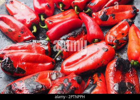 Rösten Sie köstliche rote Paprika für einen rauchigen Geschmack und schnelles Schälen. Balkansalatrezepte. Thermische Verarbeitung der Pfefferpflanze auf einem Metallkreis. Pe Stockfoto