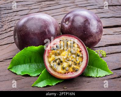 Dunkellila Passionsfrüchte und die Hälfte mit scheinbar Innenausstattung auf einem Holztisch. Stockfoto