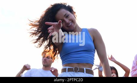 Nahaufnahme einer fröhlichen jungen, attraktiven Frau, die bei einer Sommerparty auf dem Dach tanzt und springt. Fröhliche, wunderschöne weibliche Tänze und lächelnde Stockfoto