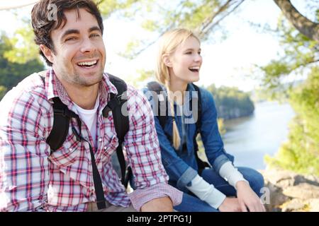 Genießen Sie einen Tag in der freien Natur. Ein gutaussehender junger Mann, der mit seiner Freundin in der Natur sitzt. Stockfoto