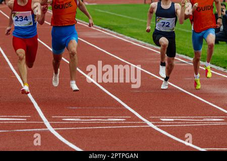 Männliche blinde para-Athleten mit Führern, die das Stadion der Ziellinie und die Sommer-Para-Athletik-Meisterschaften führen Stockfoto