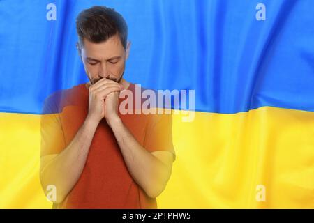 Doppelte Exposition der Nationalflagge und des betenden Mannes. Beenden Sie den Krieg in der Ukraine Stockfoto