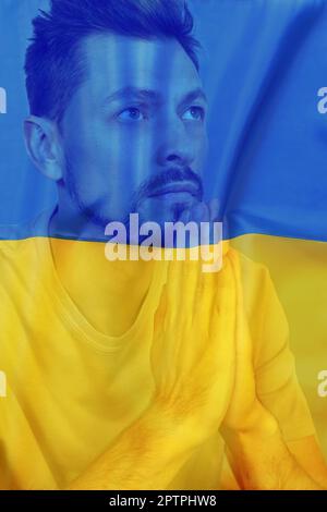 Doppelte Exposition der Nationalflagge und des betenden Mannes. Beenden Sie den Krieg in der Ukraine Stockfoto