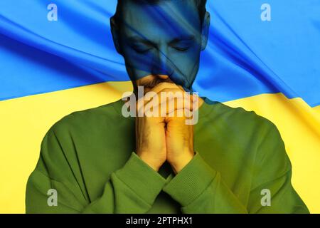Doppelte Exposition der Nationalflagge und des betenden Mannes. Beenden Sie den Krieg in der Ukraine Stockfoto
