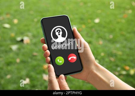 Frau mit Smartphone und einem eingehenden Anruf von einem unbekannten Anrufer im Freien, Nahaufnahme. Seien Sie vorsichtig - Betrug Stockfoto