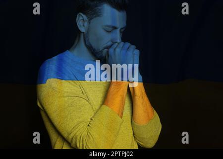Doppelte Exposition der Nationalflagge und des betenden Mannes. Beenden Sie den Krieg in der Ukraine Stockfoto