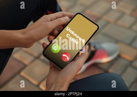 Frau mit Smartphone und einem eingehenden Anruf von einem unbekannten Anrufer im Freien, Nahaufnahme. Seien Sie vorsichtig - Betrug Stockfoto