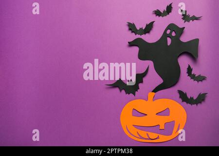 Flache Laienzusammensetzung mit Papiergeist, gruseligem Kürbis und Fledermäusen auf lila Hintergrund, Platz für Text. Halloween-Feier Stockfoto