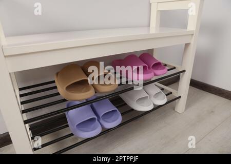 Aufbewahrungsbank mit Paar Gummipantoffeln im Zimmer Stockfoto