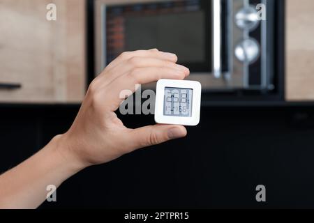 Frau mit digitalem Hygrometer und Thermometer in der Küche, Nahaufnahme Stockfoto