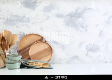 Verschiedene Geschirr und Utensilien auf weißem Marmortisch an strukturierten Wänden. Platz für Text Stockfoto