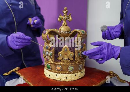 Die Cadbury World Chocolatiers Dawn Jenks und Donna Oluban verleihen der Cadbury World in Birmingham, einer 45cm m hohen Schokoladenreproduktion der St. Edward's Crown, den letzten Schliff. Es dauerte zwei Tage, um ihre Version der Krone zu bauen, die bei der Krönung von König Karl III. Mit weißer Schokolade und Milchschokolade verwendet und mit essbarem Glitzer bestaubt wird. Bilddatum: Mittwoch, 26. April 2023. Stockfoto