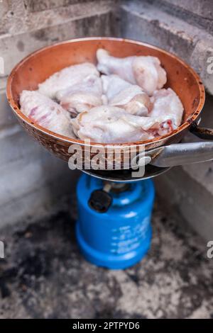 Spanische Mahlzeit im Freien. Frisch gebratene Hähnchenflügel auf einer Pfanne in einem Campinggasofen Stockfoto