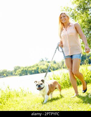 Wir gehen jeden Tag spazieren. Eine schöne Blondine, die mit ihrem Hund spazieren geht Stockfoto