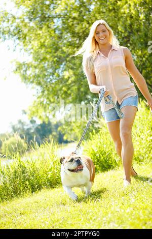 Wir bekommen beide unsere tägliche Bewegung. Eine schöne Blondine, die mit ihrem Hund spazieren geht Stockfoto