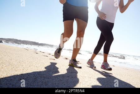 Fitness im Freien. Ein junges Paar, das am Strand joggt. Stockfoto